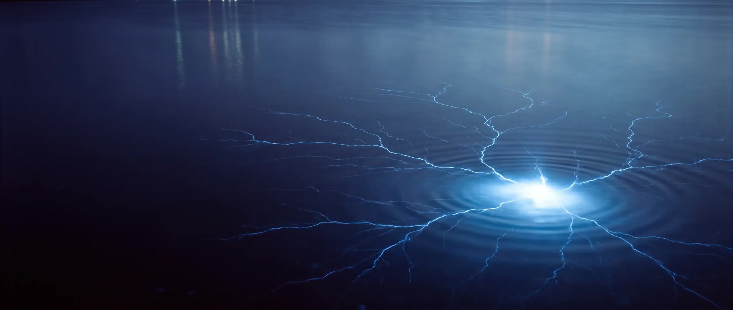 Dark blue water at night, veins of electric-blue light converging to a bright point with rings spreading from it